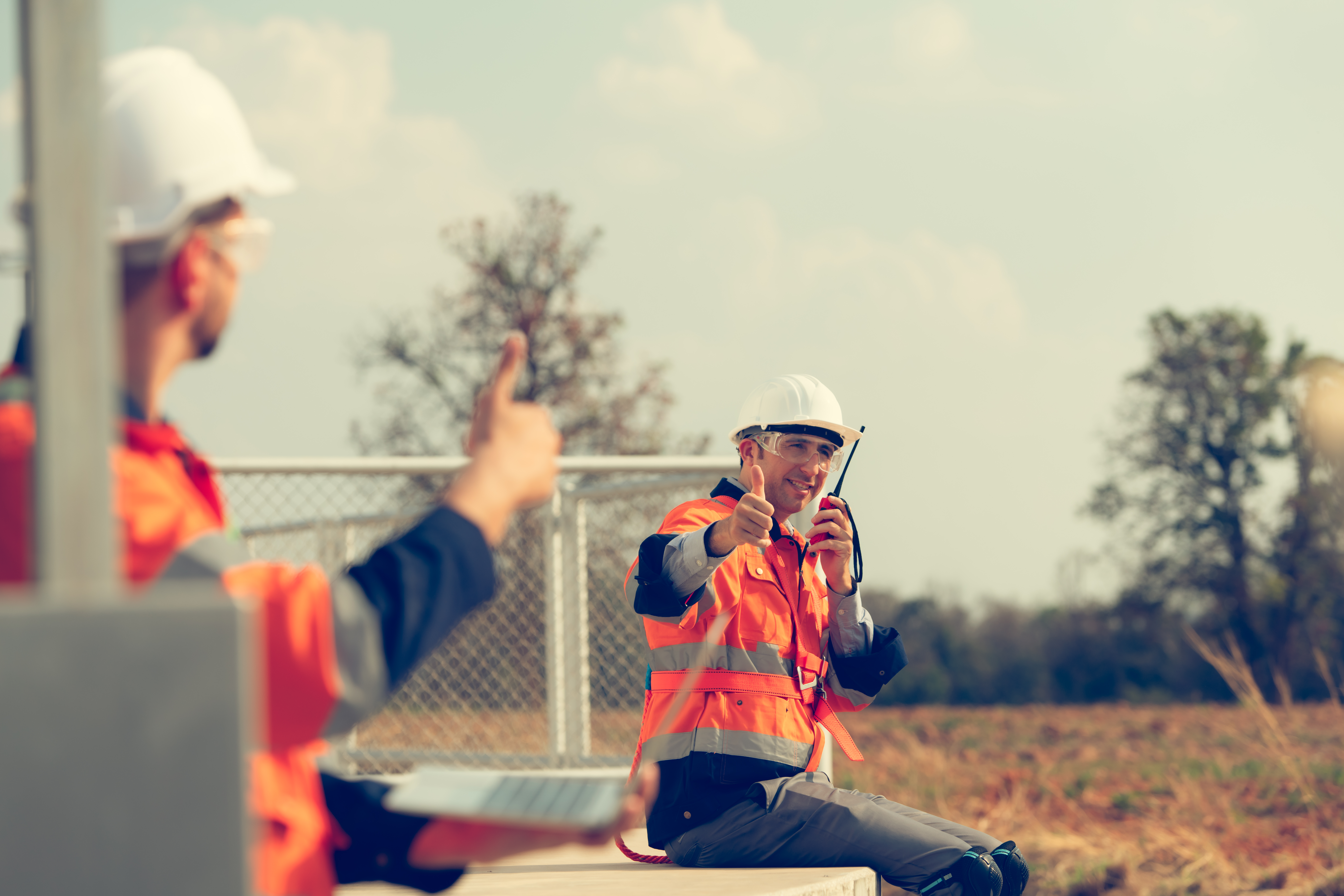 Engineer working at a wind farm for renewable energy has the responsibility of maintaining a sizable wind turbine. Encourage one another as you complete duties.